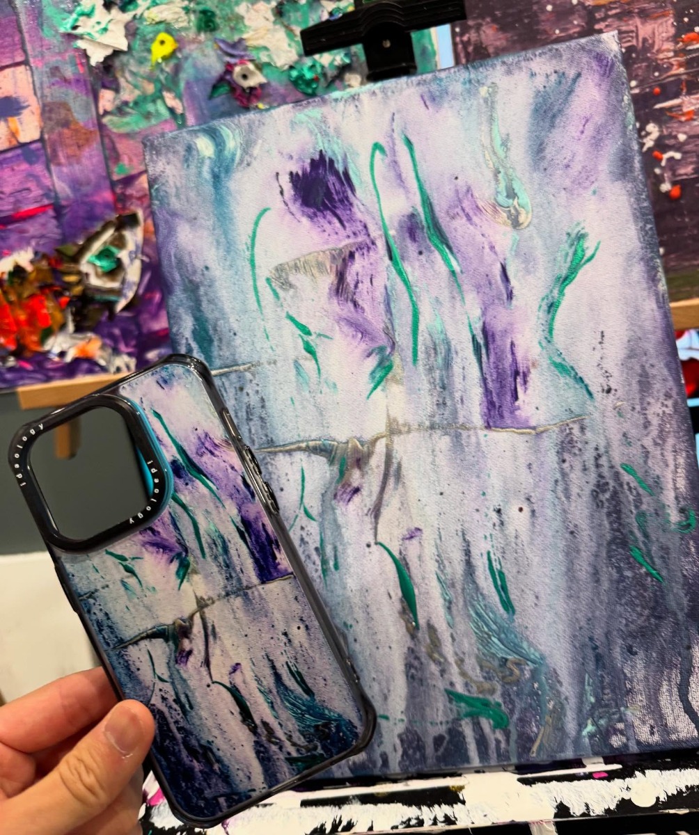 原画の前で手に持ったスマホケース